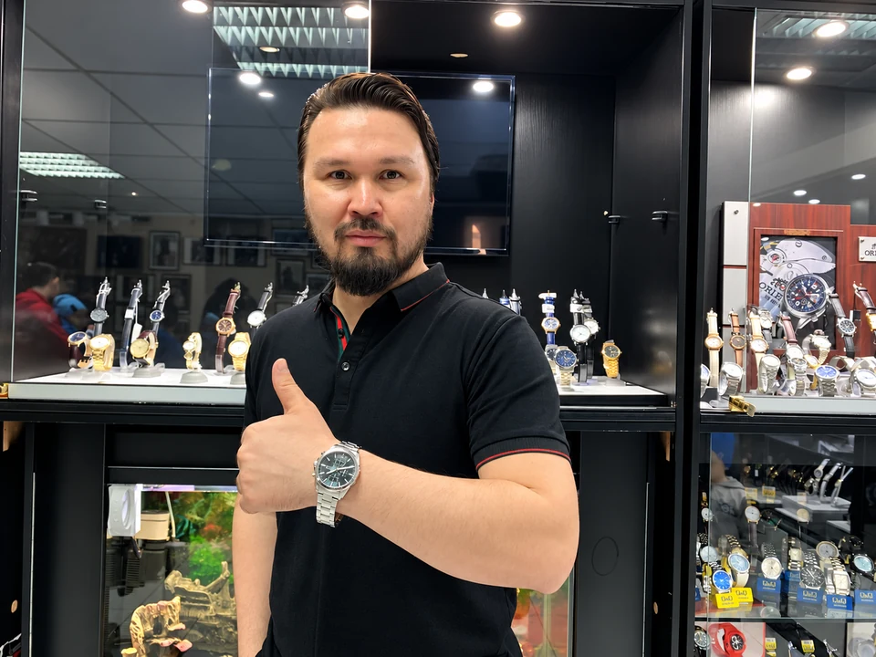 Марат Абдулаев в часовом салоне BUYTIME4U рядом с витринами и каталогами
