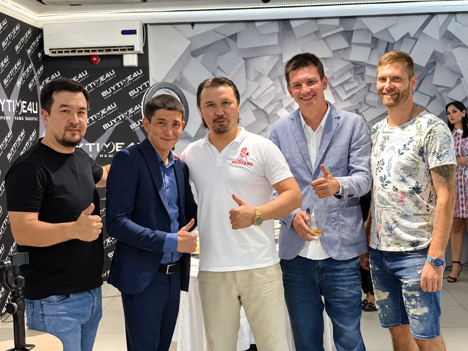 Гости стоят вместе у фирменного оформления на открытии шоурума BUYTIME4U