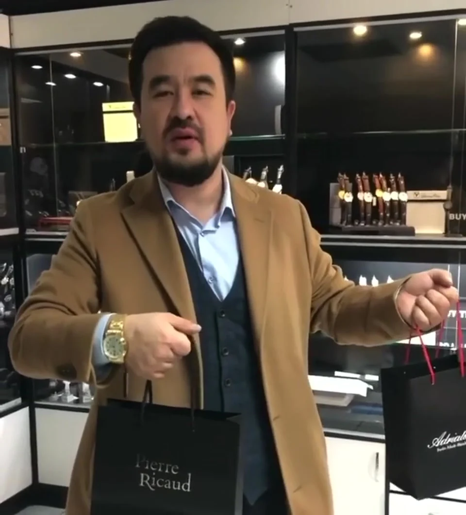 KENTAL стоит перед часовыми витринами BUYTIME4U и обращается к камере